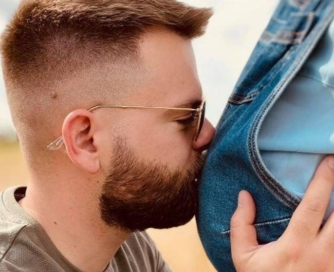 Christopher beijando a barriga de Marine, que está grávida.